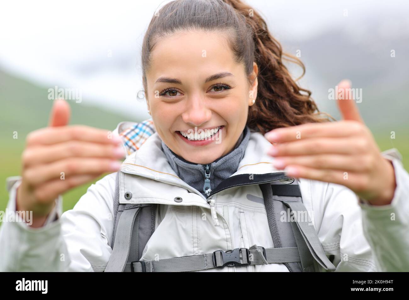 Vista frontal retrato de una feliz excursionista que invita a decir Venga aquí con sus manos Foto de stock