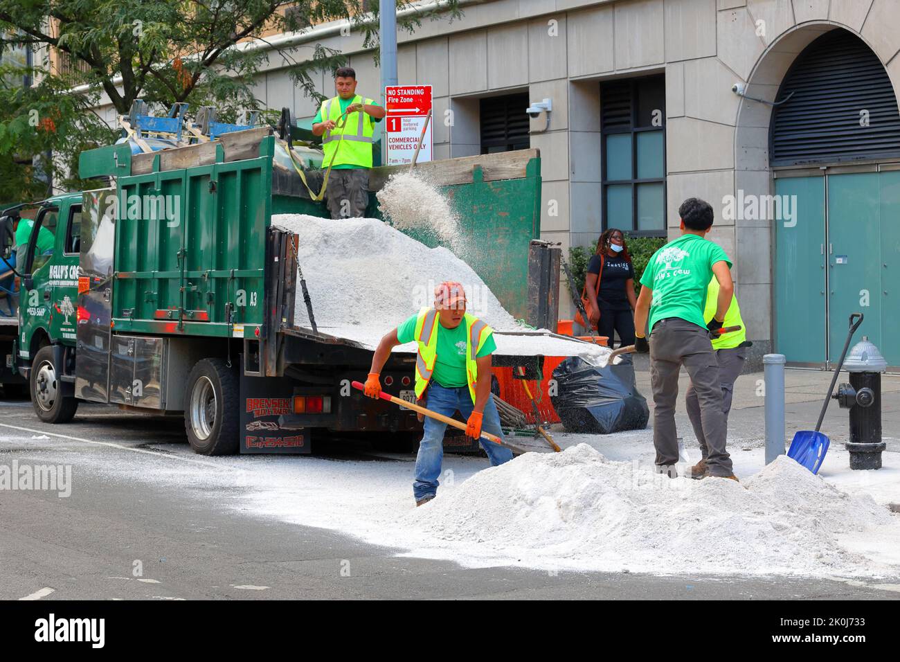 Los trabajadores de paisajismo echan una pila de piedra caliza triturada a la parte trasera de un camión en la ciudad de Nueva York. Foto de stock