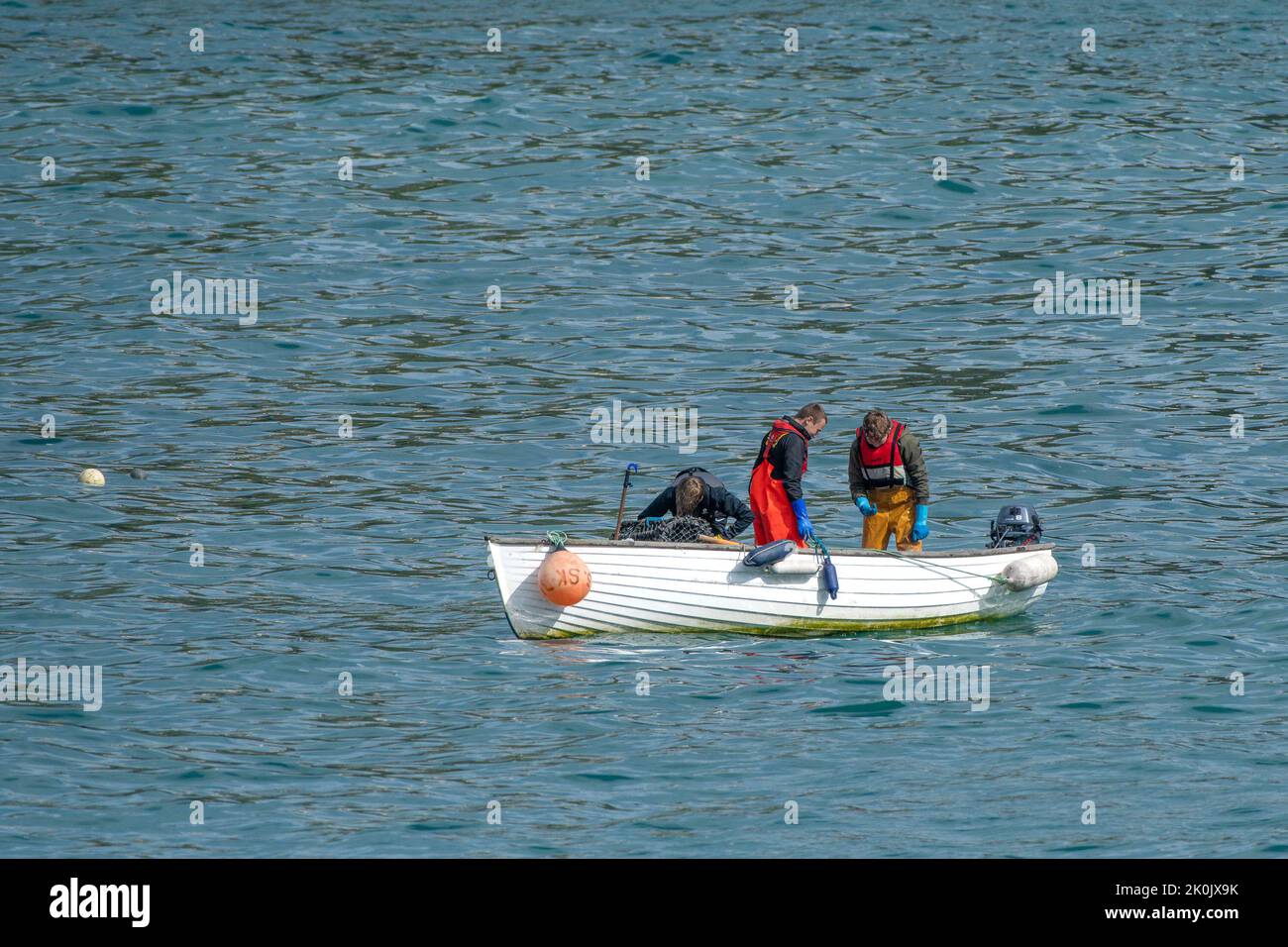 Tres pescadores en un barco frente a la costa en Newquay, en Cornwall, Reino Unido. Foto de stock