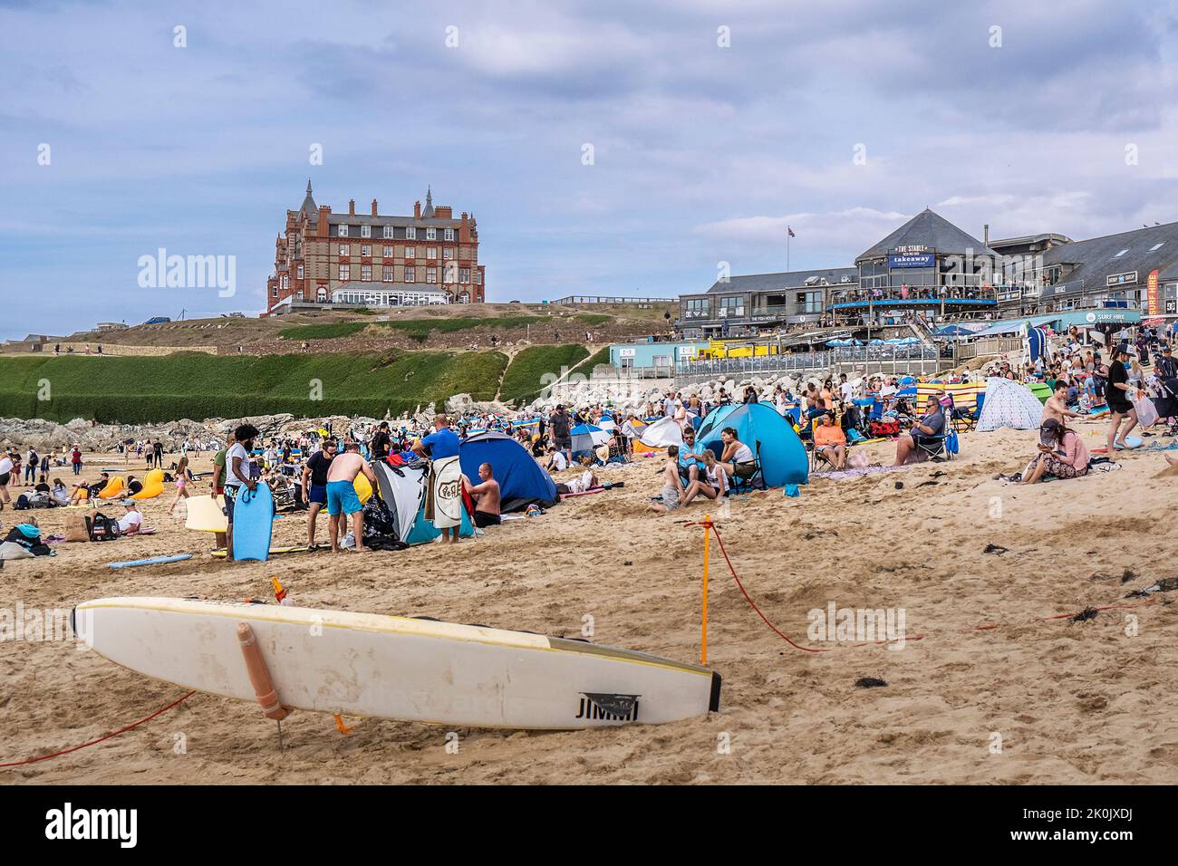 Turistas relajándose y disfrutando en un concurrido Fistral Beach Newquay en Cornwall en el Reino Unido. Foto de stock
