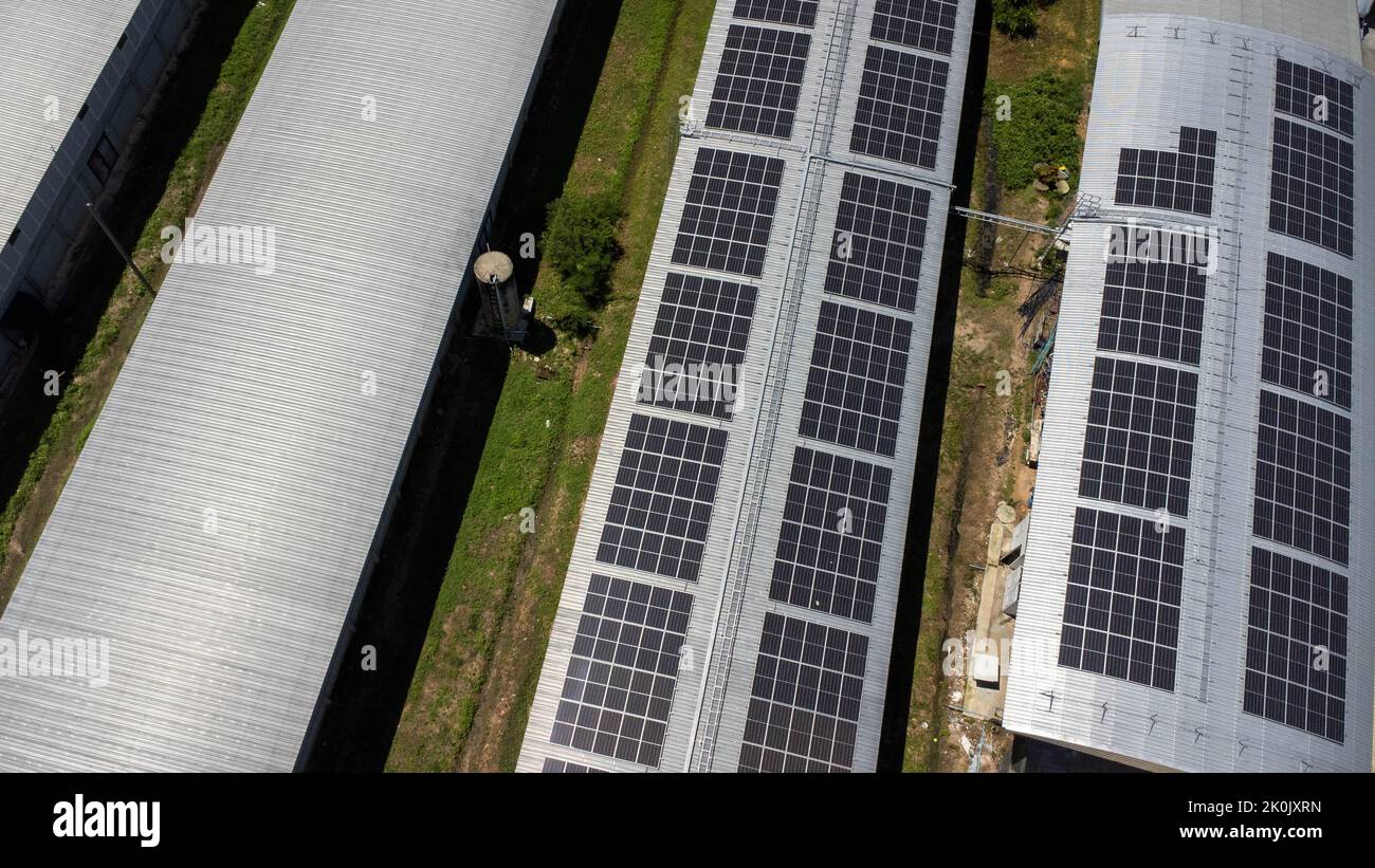 Vista aérea de los paneles solares instalados en el techo de un gran edificio industrial o de un almacén. Vista superior de central solar con fábrica. Sustainab Foto de stock