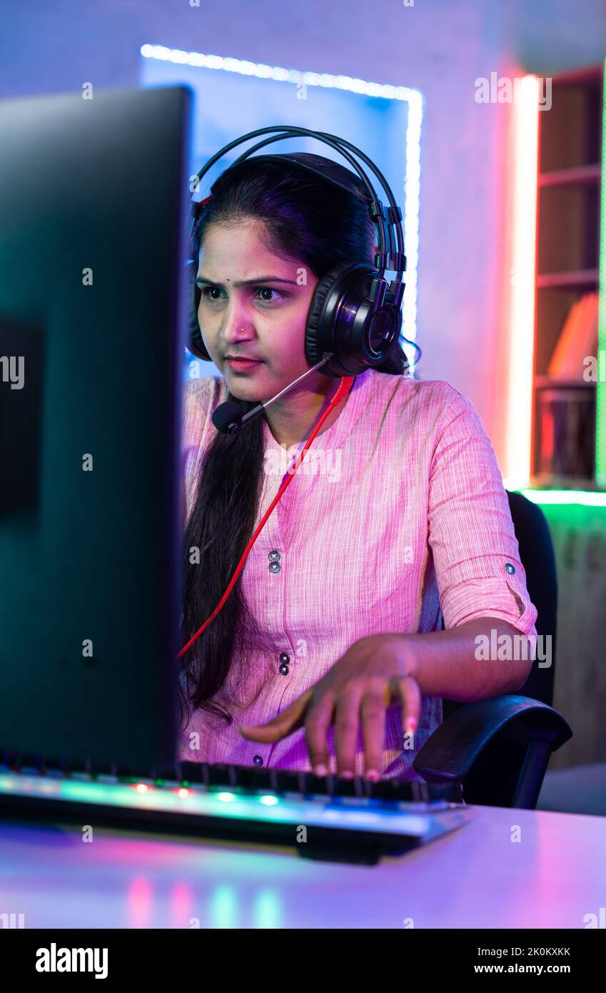 Mujer jugando video juego en vivo en el ordenador hablando con los jugadores en los auriculares en casa - concepto de streaming en vivo, vlogger y torneo. Foto de stock