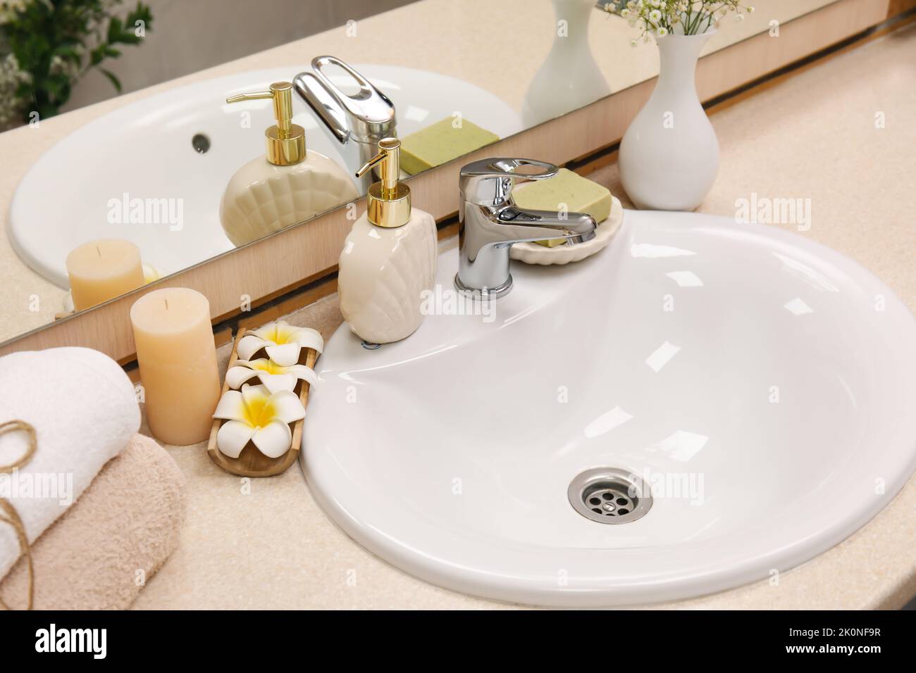Fregadero con accesorios de baño y flores en la mesa cerca de la pared de  madera en el baño Fotografía de stock - Alamy