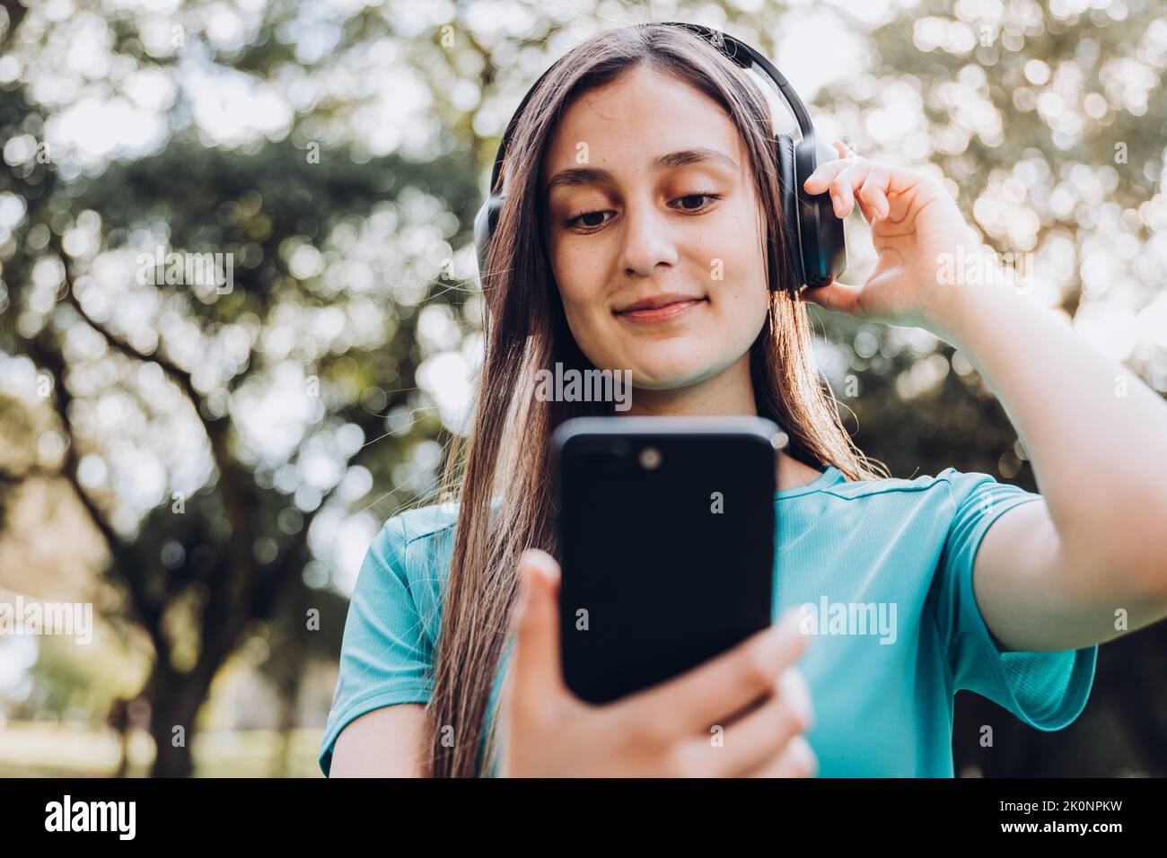 Una niña pequeña con auriculares inalámbricos negros grandes sobre un fondo  rosa pastel mira la cámara. El concepto de escuchar y disfrutar de la  música. Colocar para texto, espacio de copia Fotografía de stock - Alamy