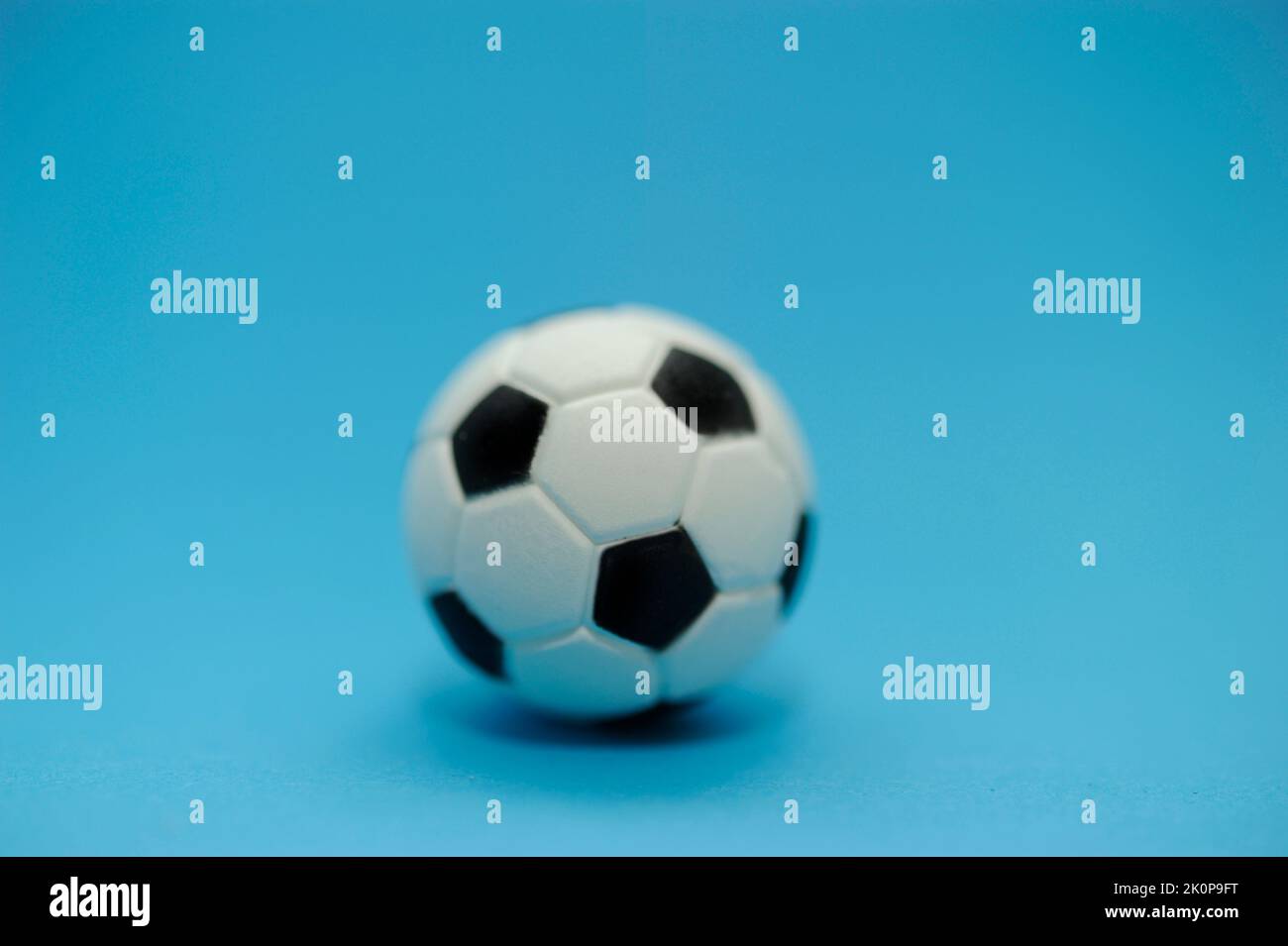 balón de fútbol en miniatura sobre fondo azul Foto de stock