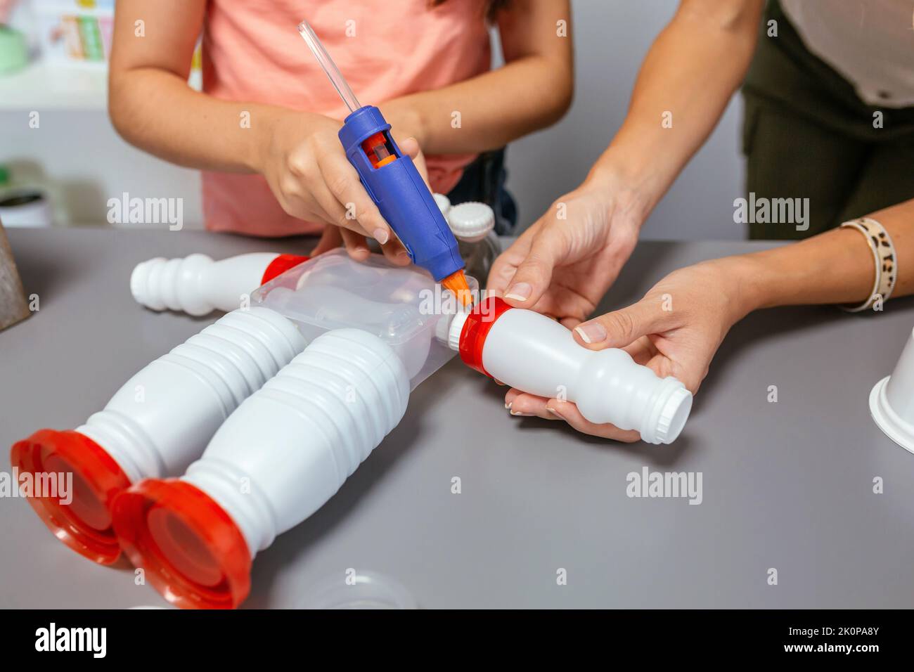 Estudiante y profesor haciendo robot de juguete reciclado con pistola de adhesivo termofusible Foto de stock