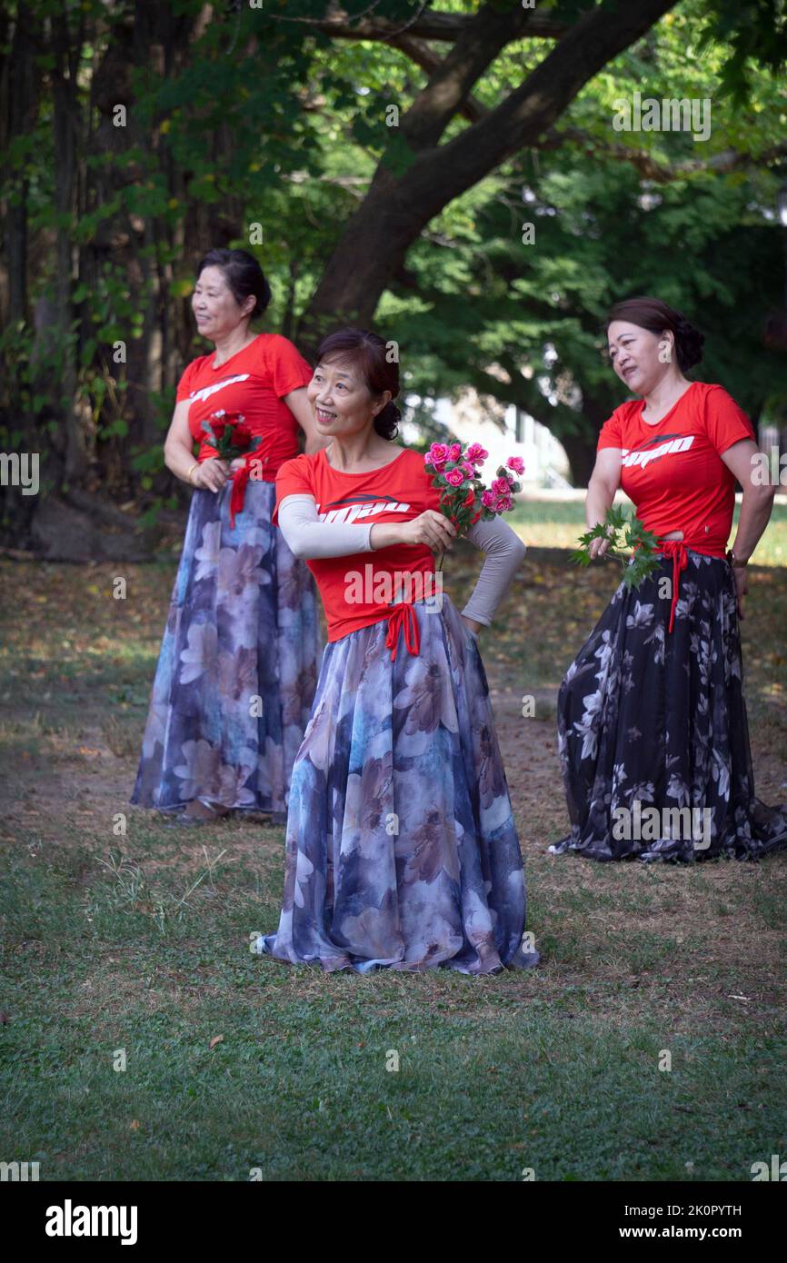 Forma parte de un gran grupo de mujeres chinas americanas en una clase de baile y ejercicio yuanji en un parque de Queens, Nueva York. Es una tradición matutina china. Foto de stock