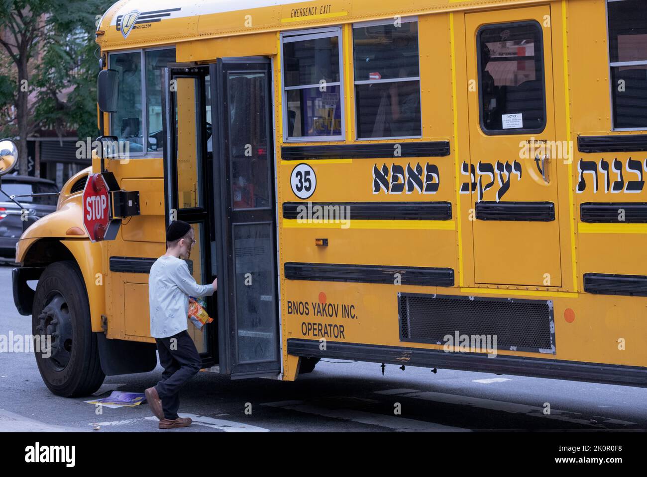 Un joven escolar del grupo Pupa hasidic sube a bordo de un autobús escolar a su yeshiva. En Lee Avenue en Williamsburg, Brooklyn, Nueva York Foto de stock