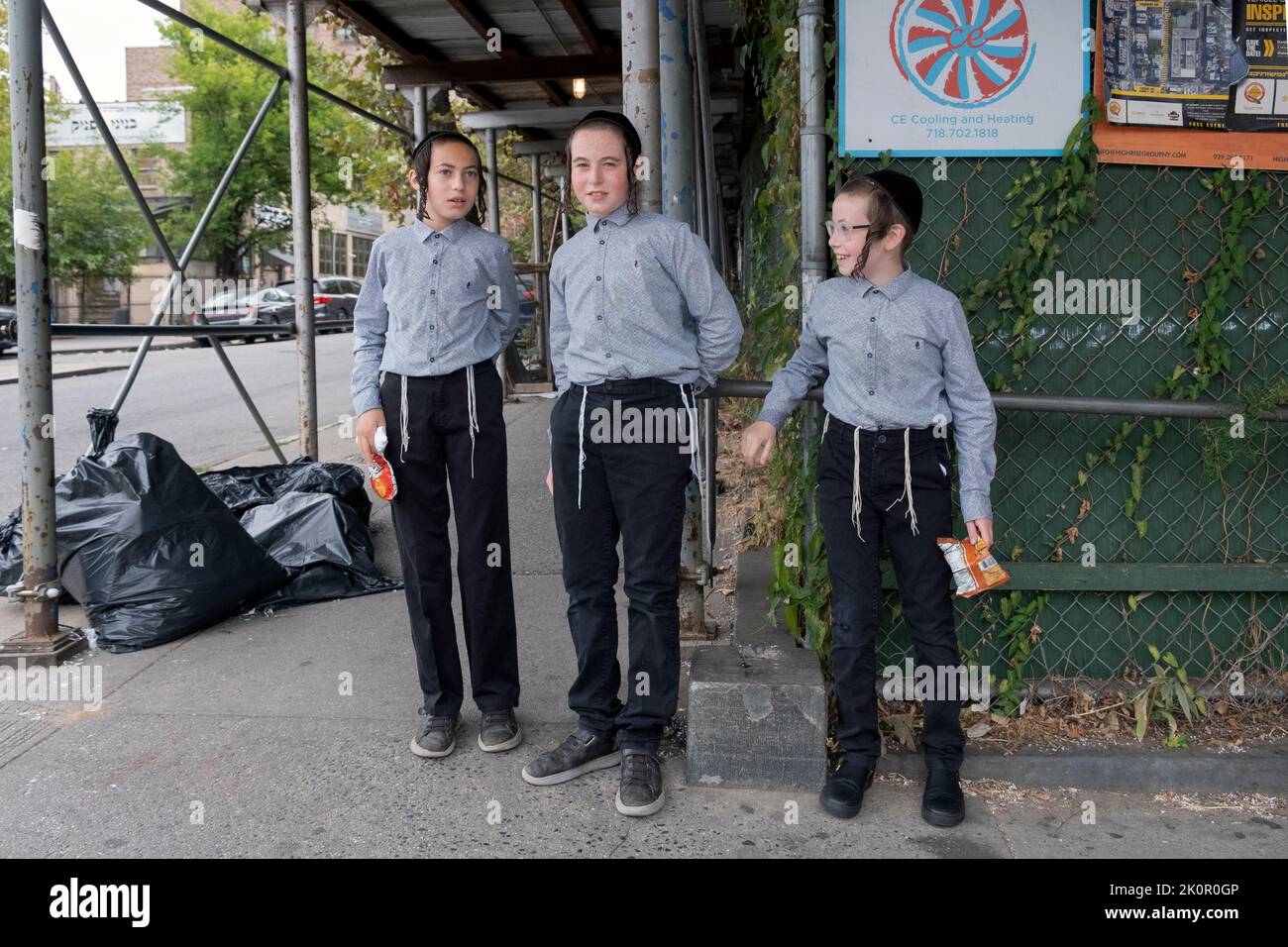 3 hermanos judíos ortodoxos esperan su autobús escolar en Lee Avenue en Williamsburg, Brooklyn, Nueva York. Foto de stock