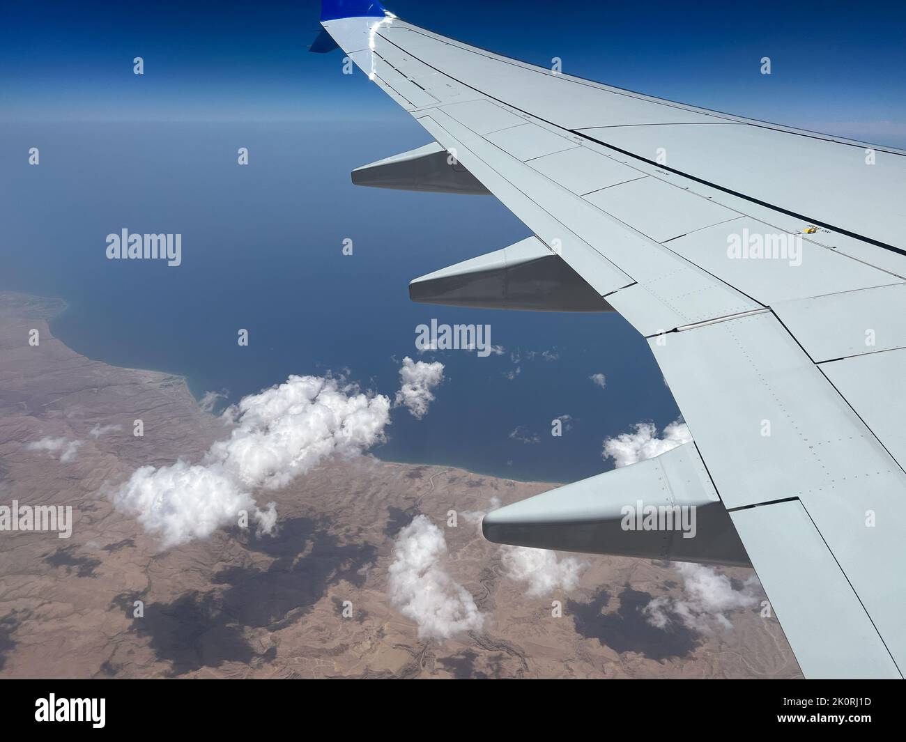 Vista de una sección del ala del avión y hermosas nubes flotantes vistas desde la ventana del avión durante el vuelo medio. Foto de stock