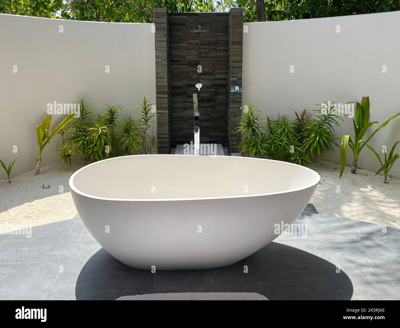 Vista de una gran bañera ovalada en un cuarto de baño con ducha abierta en una villa de lujo frente al mar en las Maldivas. Foto de stock