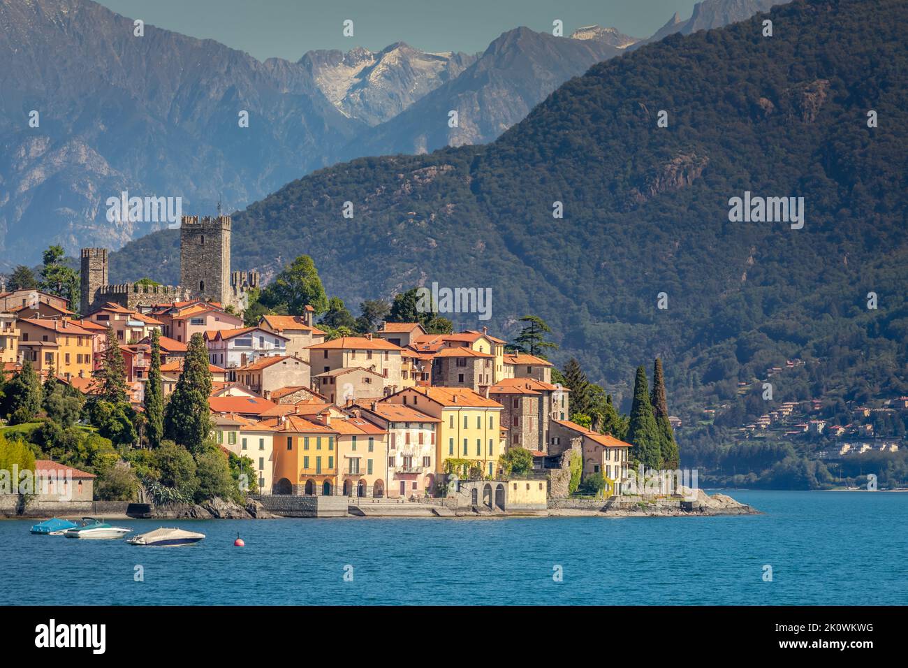Idílica costa del Lago Como con pueblo y lancha motora en un día soleado, Italia Foto de stock