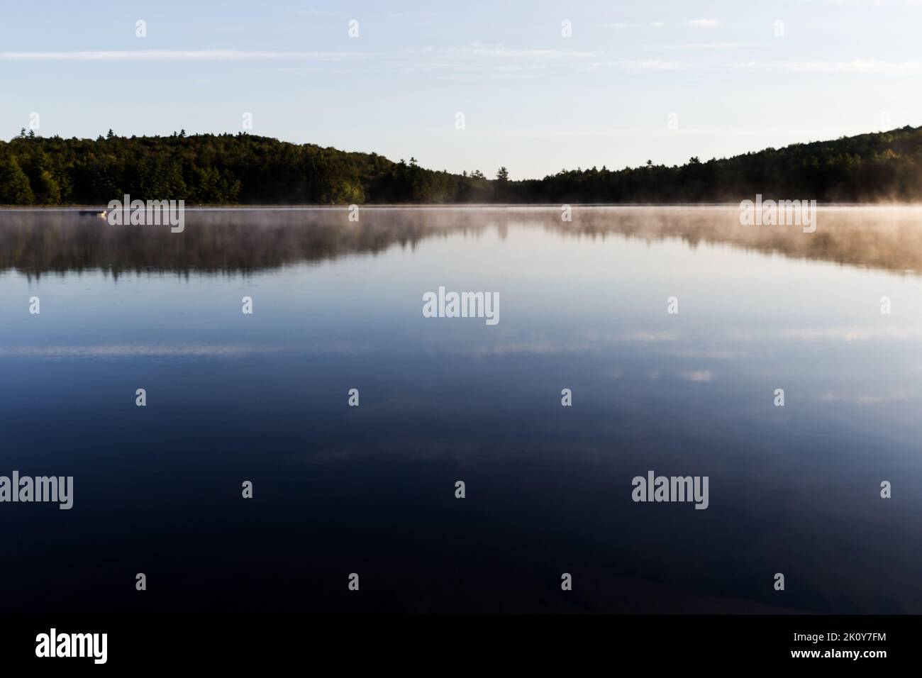 Calma temprano en la mañana en el Lago Swan en Maine con niebla en la superficie al amanecer a finales de la primavera. Foto de stock