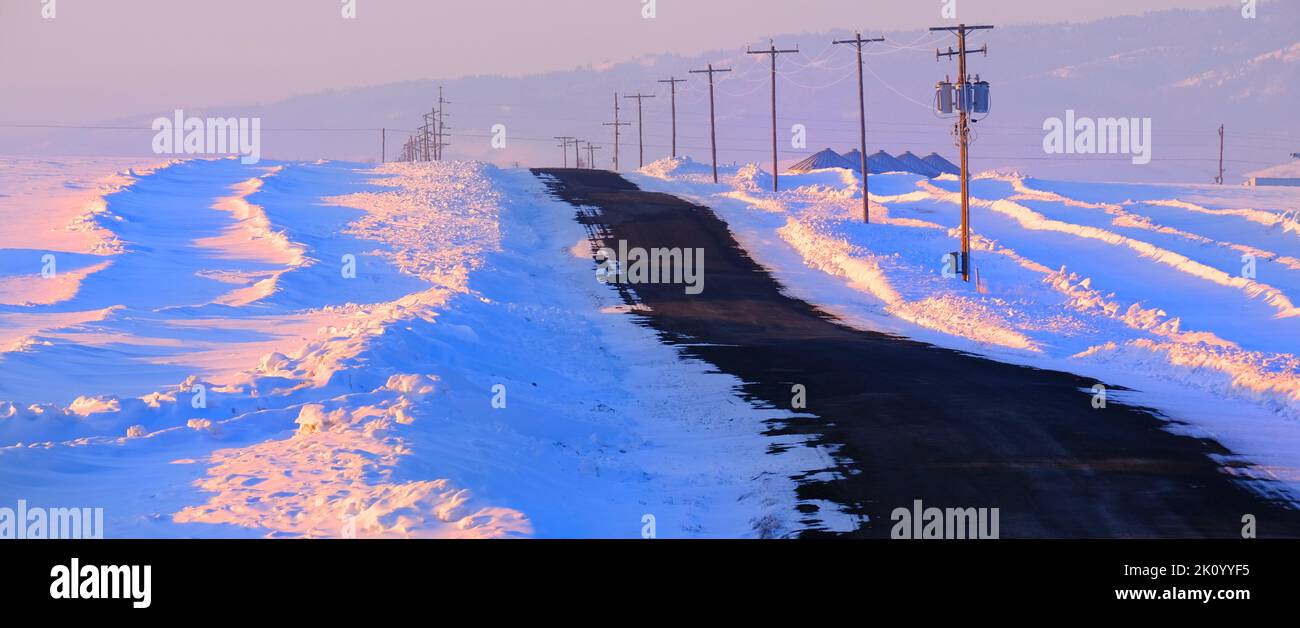 Carretera solitaria del país vacía de tráfico en el invierno con líneas eléctricas Foto de stock