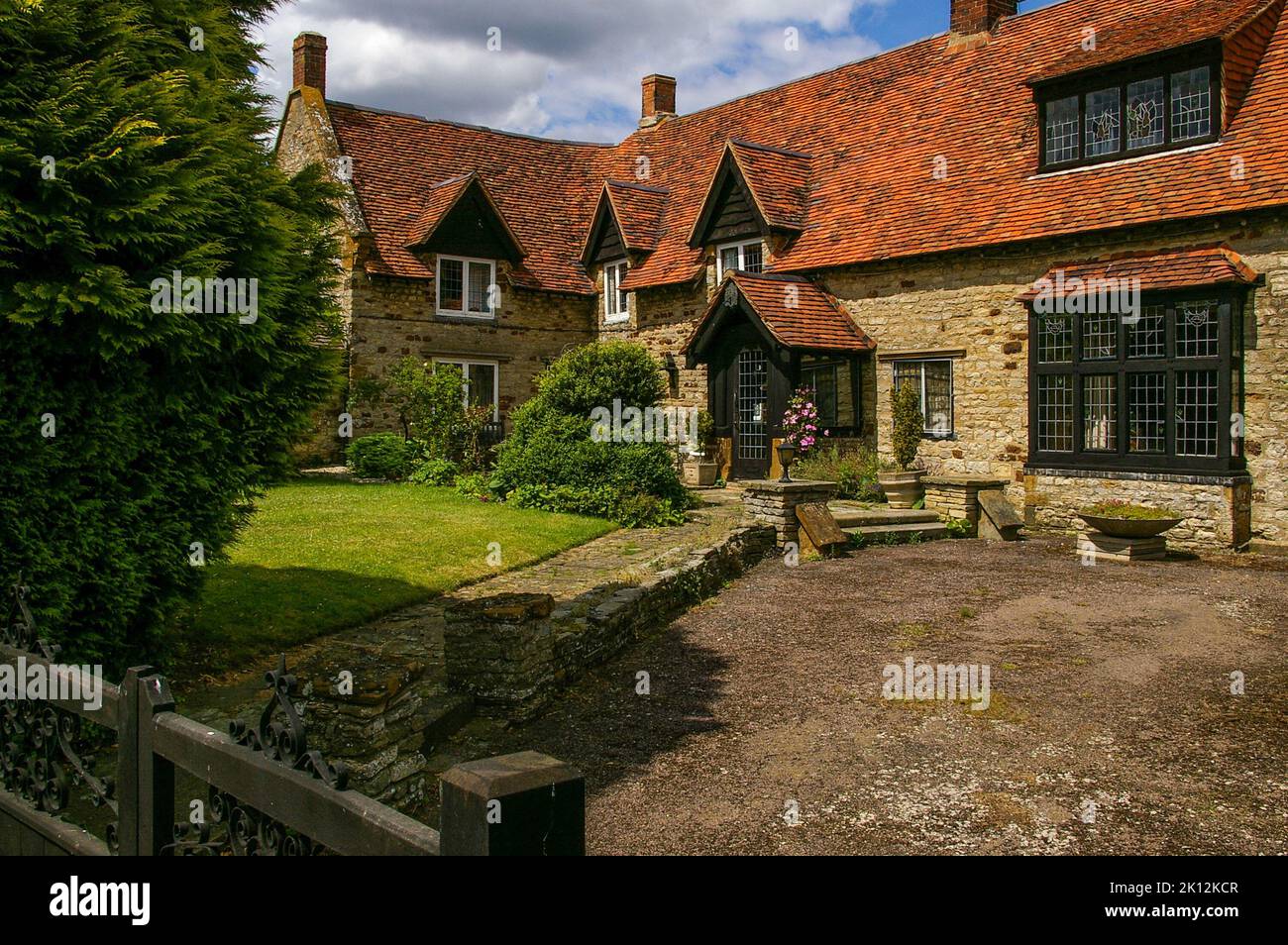 Propiedad de época separada construida en piedra con un techo de tejas rojas en el pueblo de Brafield, Northamptonshire, Reino Unido Foto de stock