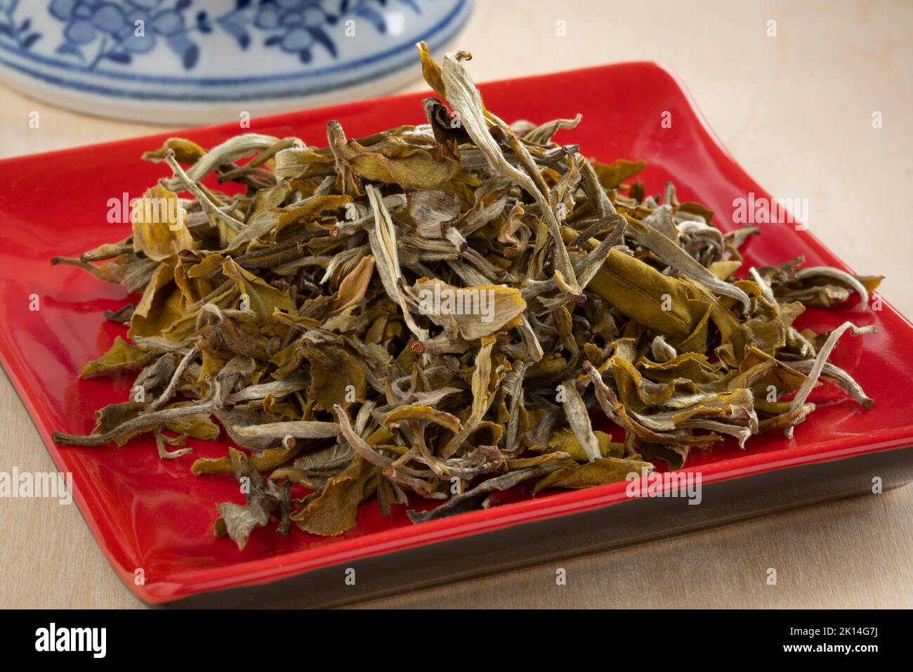 Montón de hojas de té de brotes de nieve chinos secos en un plato de primer plano Foto de stock