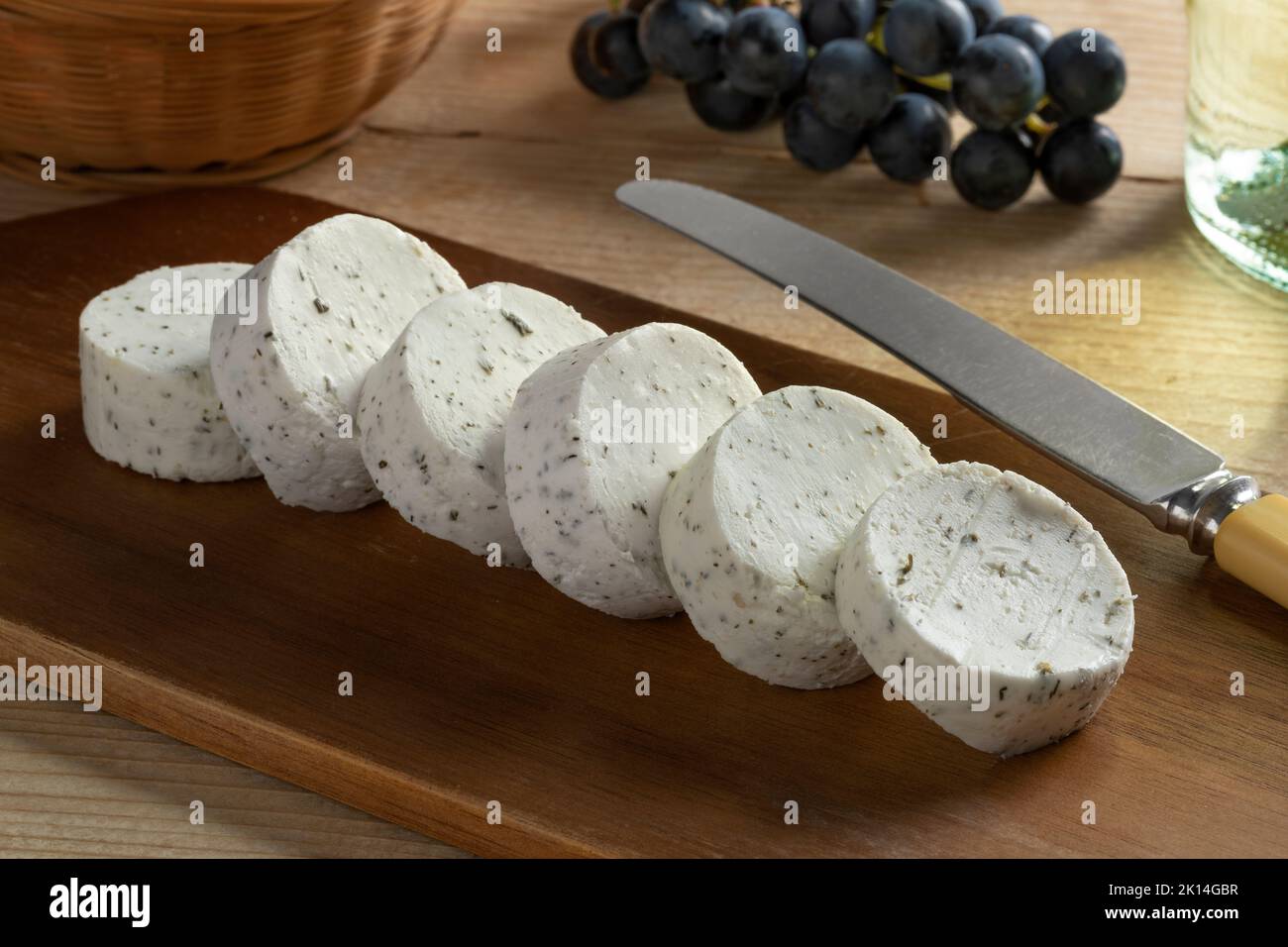 Rebanadas de queso de cabra holandés suave con hierbas de primer plano en una tabla de cortar Foto de stock
