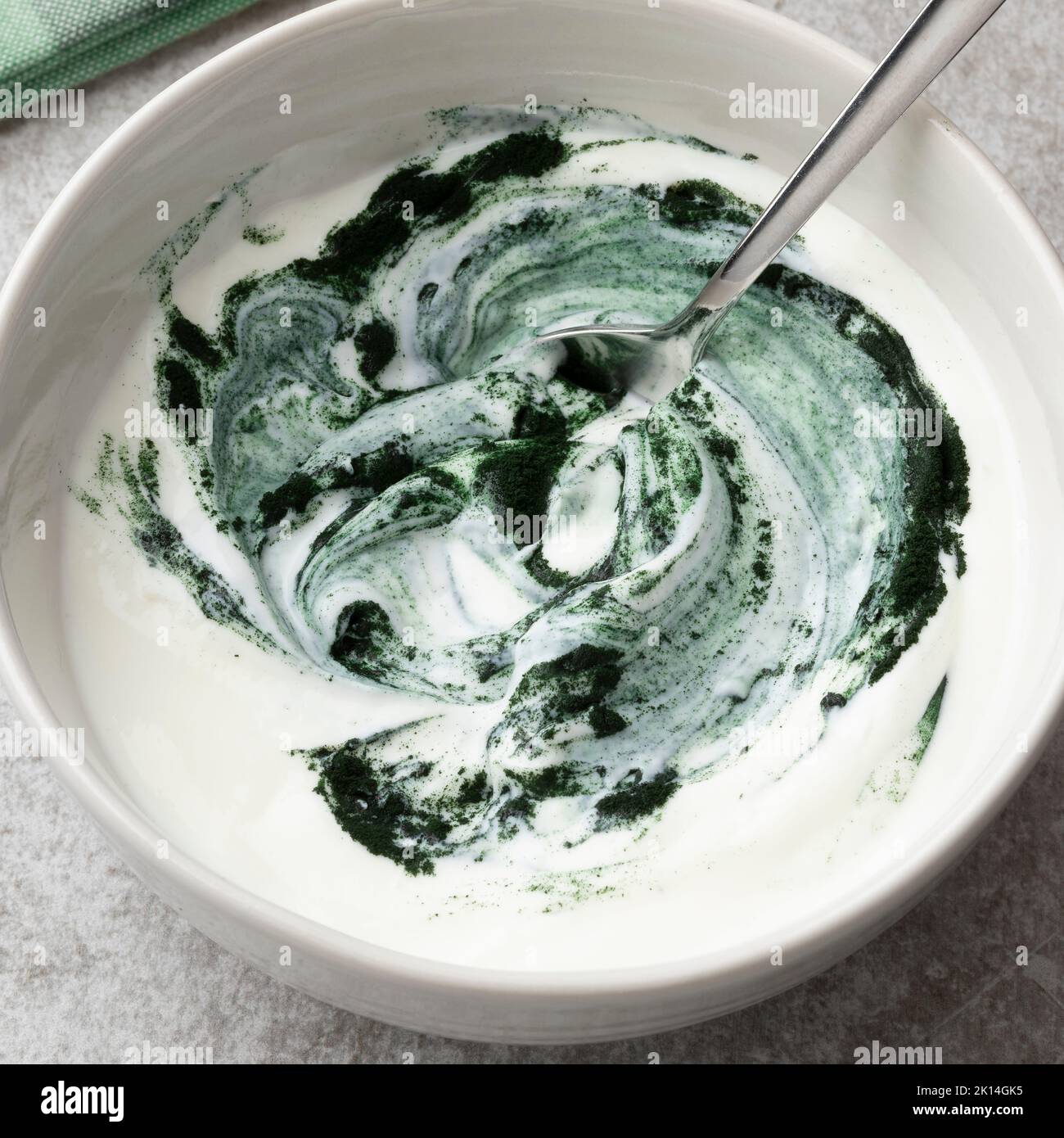 Un tazón de yogur con polvo de espirulina verde saludable para el desayuno Foto de stock