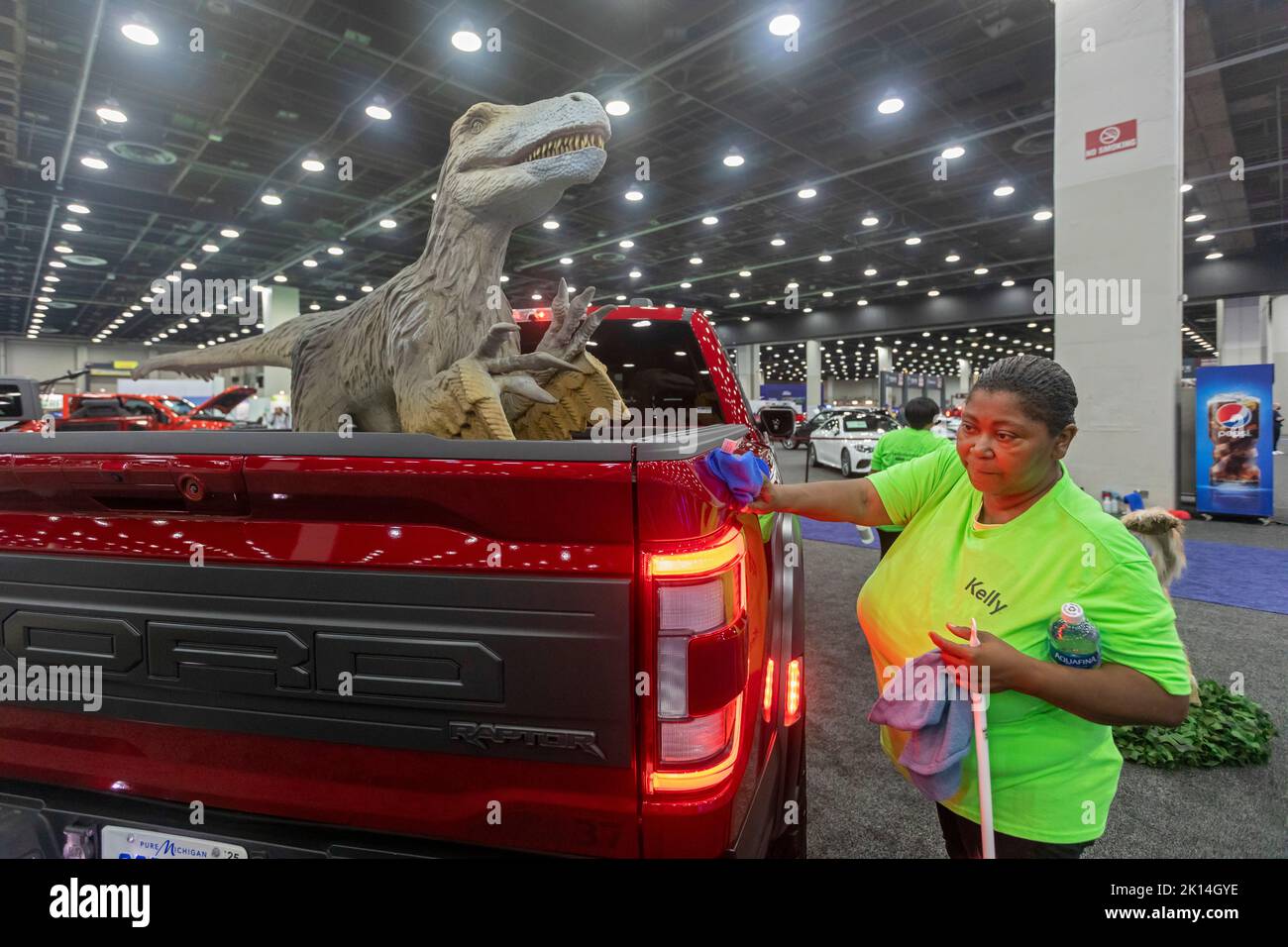 Detroit, Michigan, EE.UU. 14th de Sep de 2022. Un trabajador mantiene un ojo en el dinosaurio cercano mientras pule una camioneta Ford Raptor en el Salón Internacional del Automóvil de América del Norte. Ford añadió una bandada de dinosaurios a su exposición. Crédito: Jim West/Alamy Live News Foto de stock
