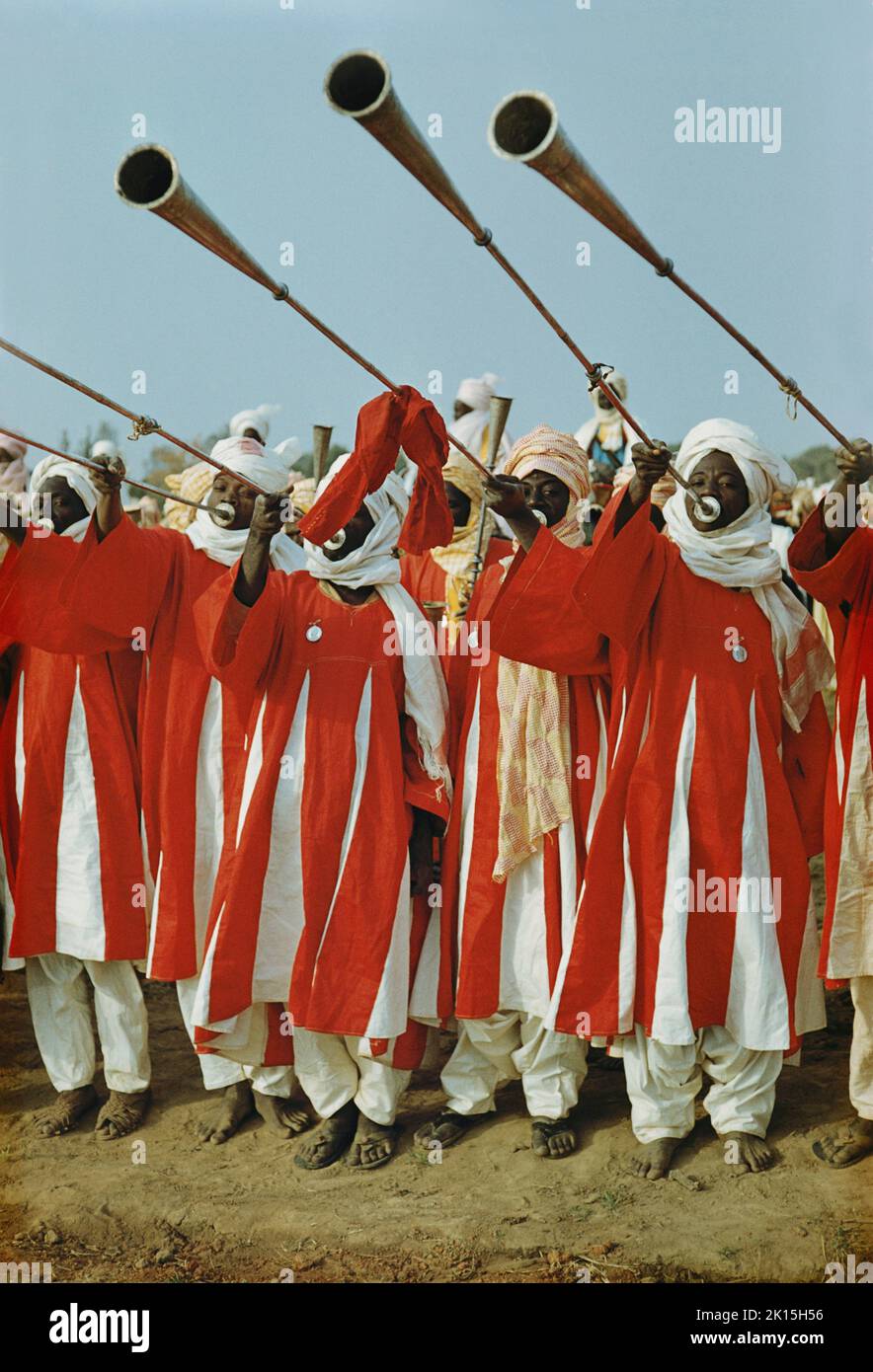Retenedores del Etsu (o líder) del pueblo Nupe en Níger, soplando una fanfarria sobre trompetas de bronce llamadas kakati. Foto de stock