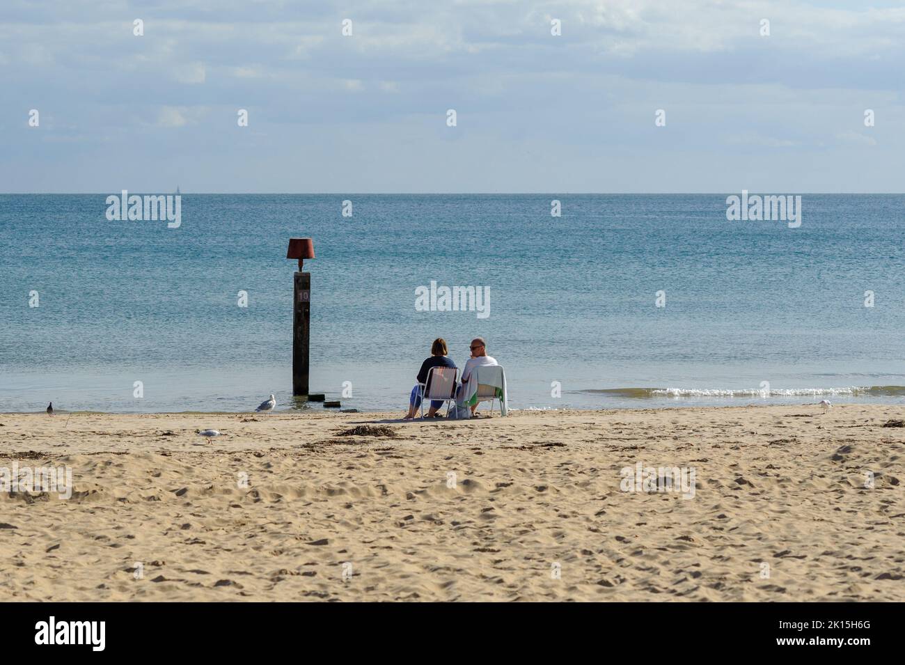Bournemouth, Dorset, Inglaterra, Reino Unido, 15th de septiembre de 2022, El tiempo. Todo es tranquilo en la playa durante la tarde al sol de principios de otoño. Una pareja se sienta en sillas a la orilla del agua. Crédito: Paul Biggins/Alamy Live News Foto de stock