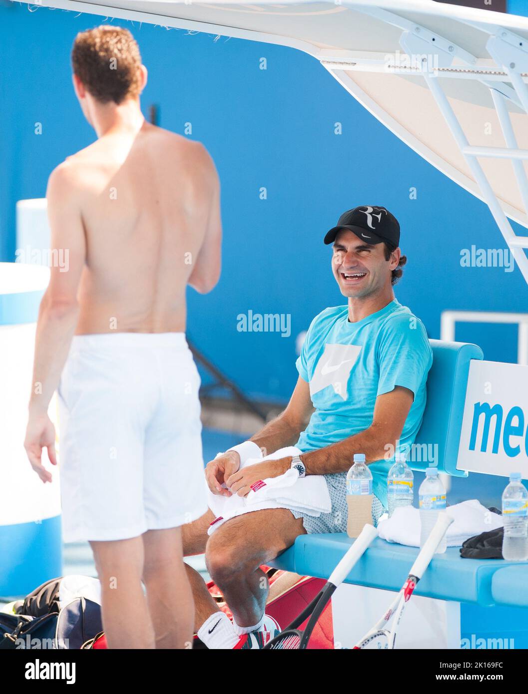 Roger Federer de Suiza casi puede tomarse un día libre mientras espera las semifinales en el Abierto de Australia de 2014 - pero todavía se mete en un poco de práctica de golpes y se ríe con un compañero de entrenamiento en el Parque Olímpico de Melbourne. Foto de stock