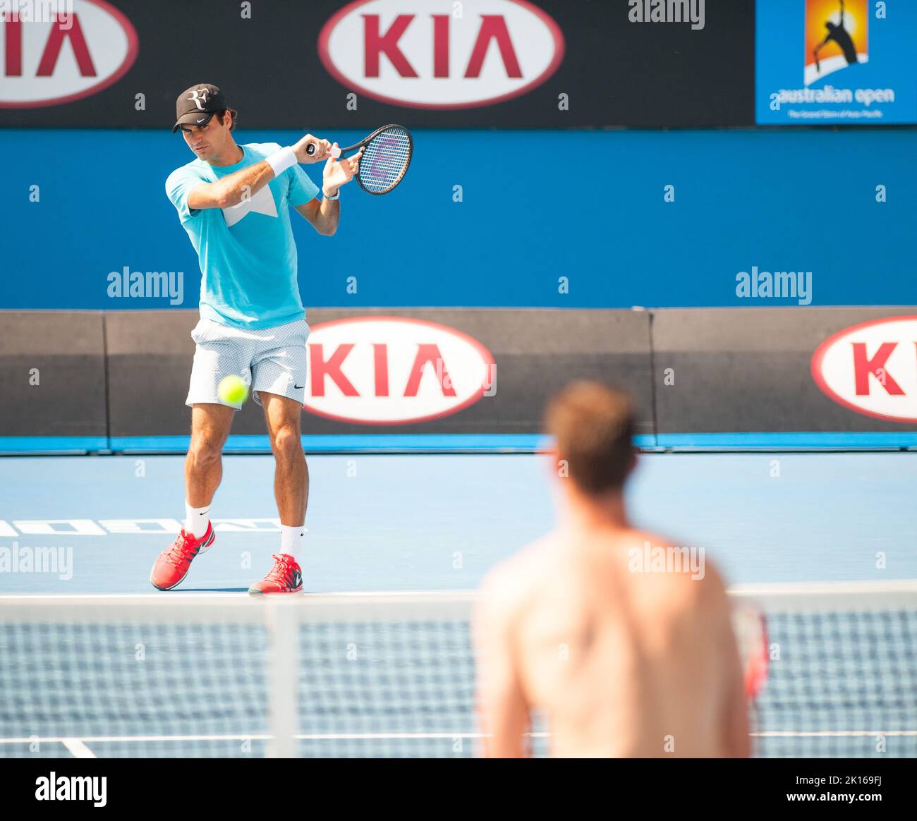 Roger Federer de Suiza casi puede tomarse un día libre mientras espera las semifinales en el Abierto de Australia de 2014 - pero todavía se mete en un poco de práctica de golpes y se ríe con un compañero de entrenamiento en el Parque Olímpico de Melbourne. Foto de stock