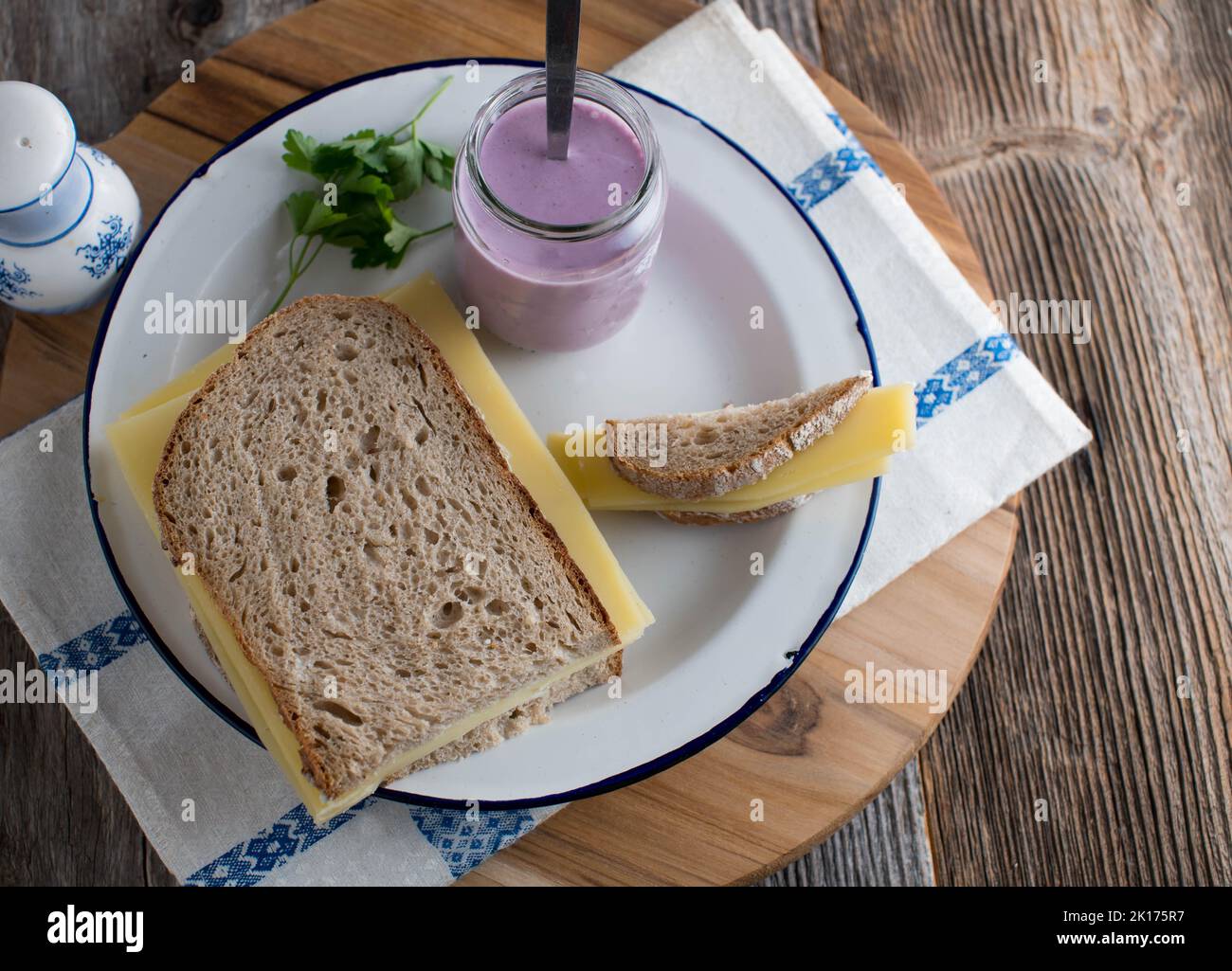 Sándwich de queso con pan de masa fermentada y gouda vieja. Servido con yogur para el desayuno en un plato Foto de stock