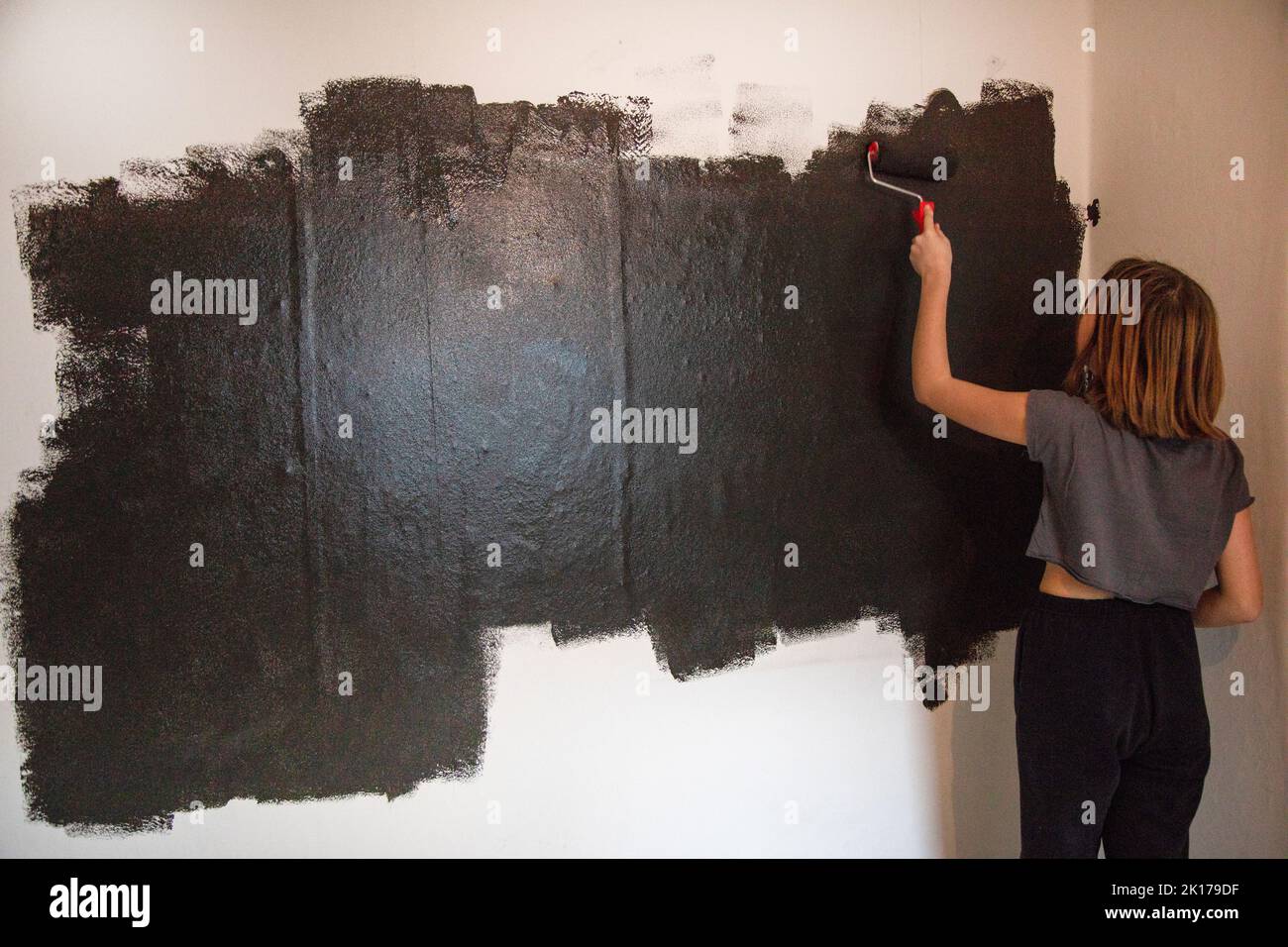 Mujer pintando la pared de negro Foto de stock