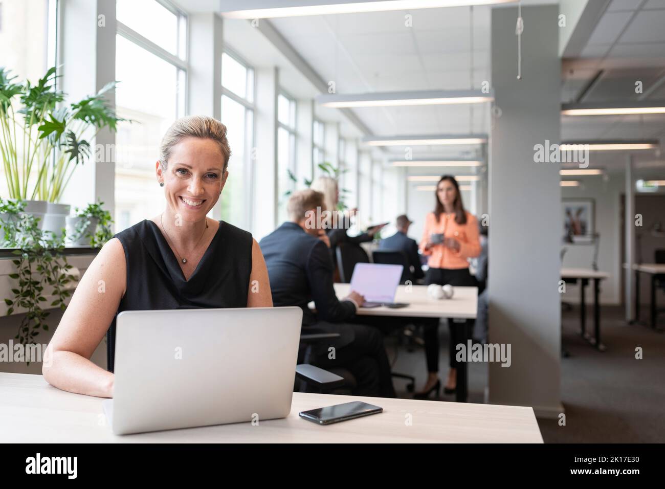 La empresaria sonriendo con laptop en la oficina Foto de stock