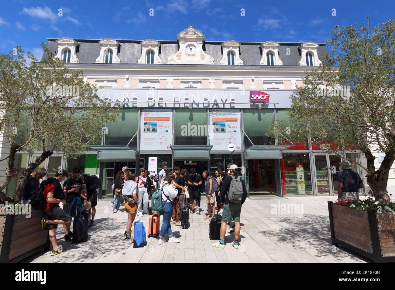 Hendaye, País Vasco Francés, Francia : Un grupo de personas se encuentra fuera de la estación de ferrocarril Gare d'Hendaye. Foto de stock
