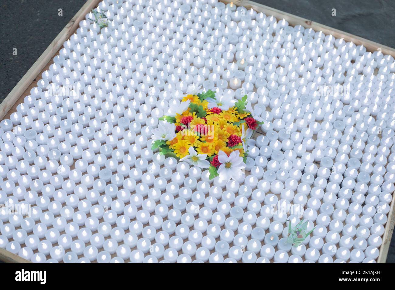 Una plataforma con muchas pequeñas velas blancas iluminadas decoradas con flores en la Ceremonia de la Paz con Linternas Flotantes en Olympic Plaza, Calgary, Canadá Foto de stock