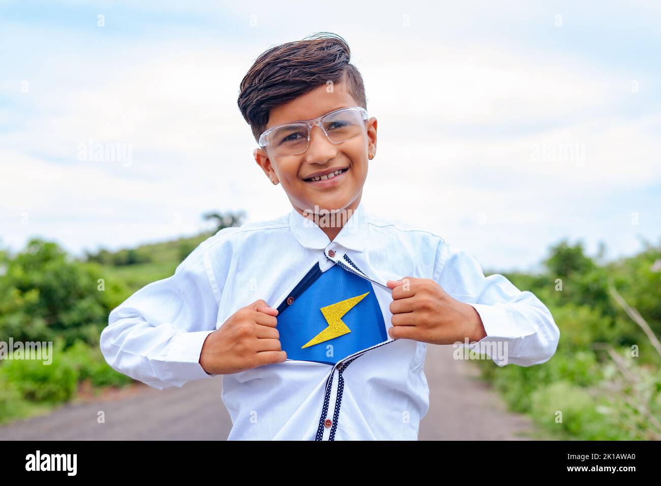 Niño feliz mostrando super poder eliminando el botón de la camisa - concepto de fantasía, Halloween e inspiración Foto de stock