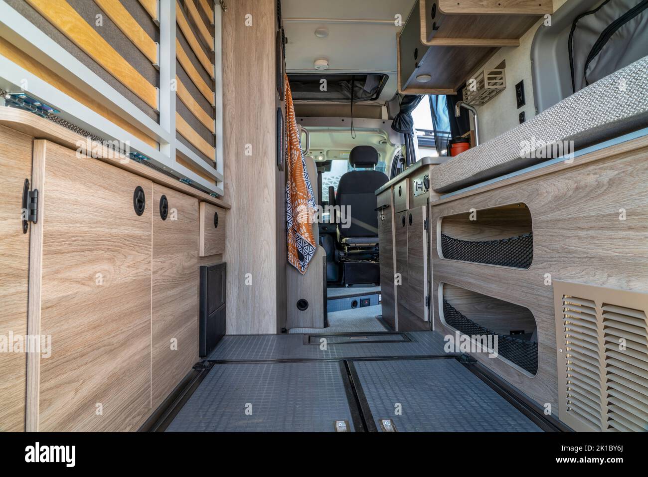 interior de furgoneta autocaravana con zona de carga, cama plegable y cocina Foto de stock