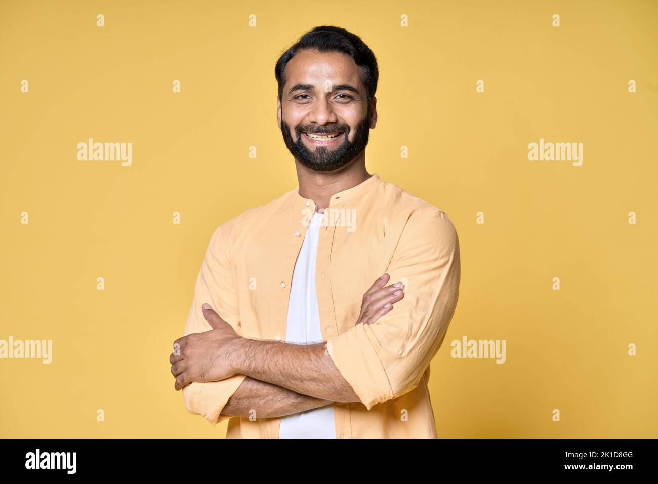 Sonriente hombre indio barbudo seguro de pie aislado sobre fondo amarillo. Foto de stock