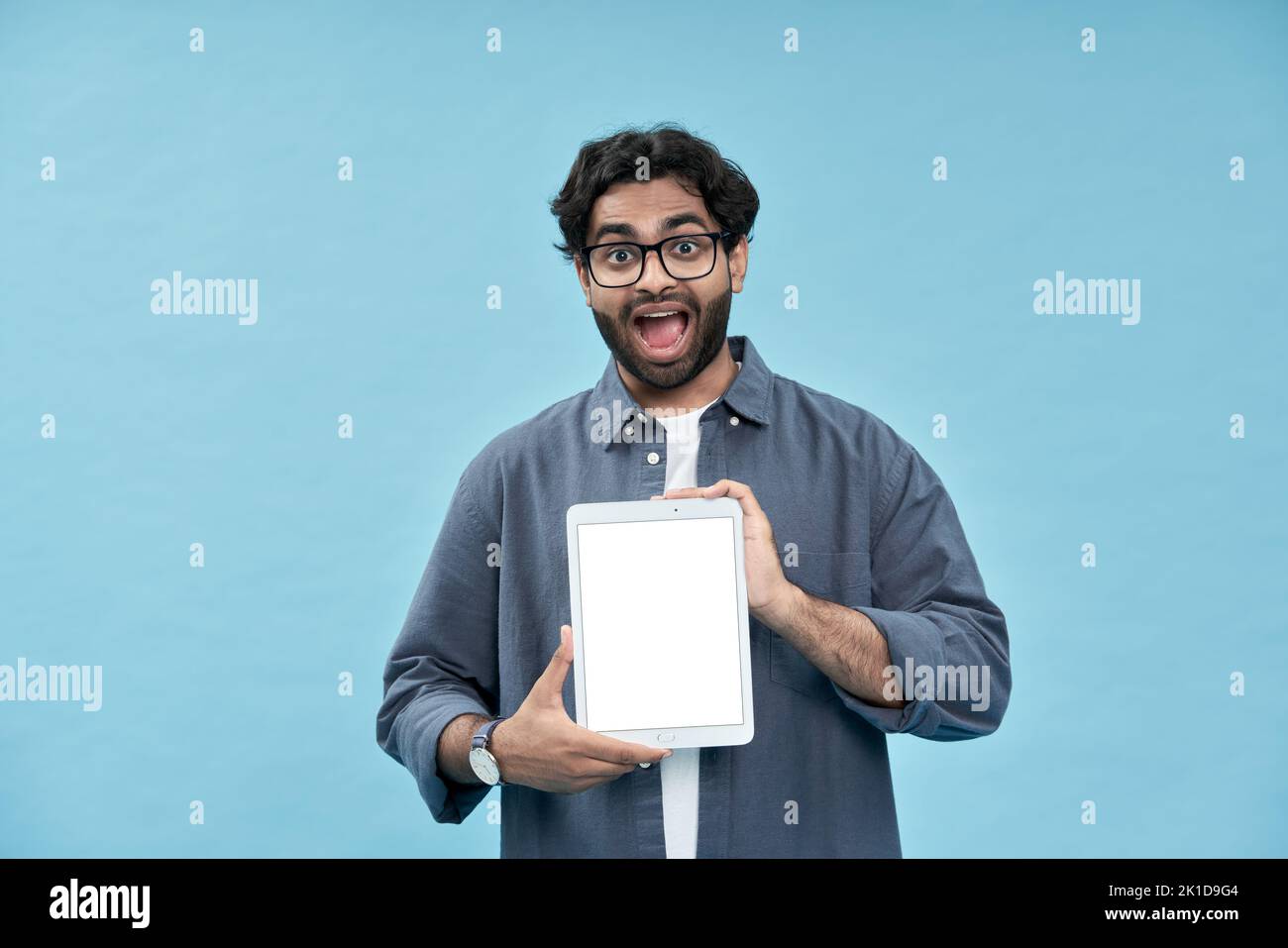 Excitado estudiante árabe mostrando la pantalla de maqueta de la tableta digital presentando el anuncio en línea. Foto de stock