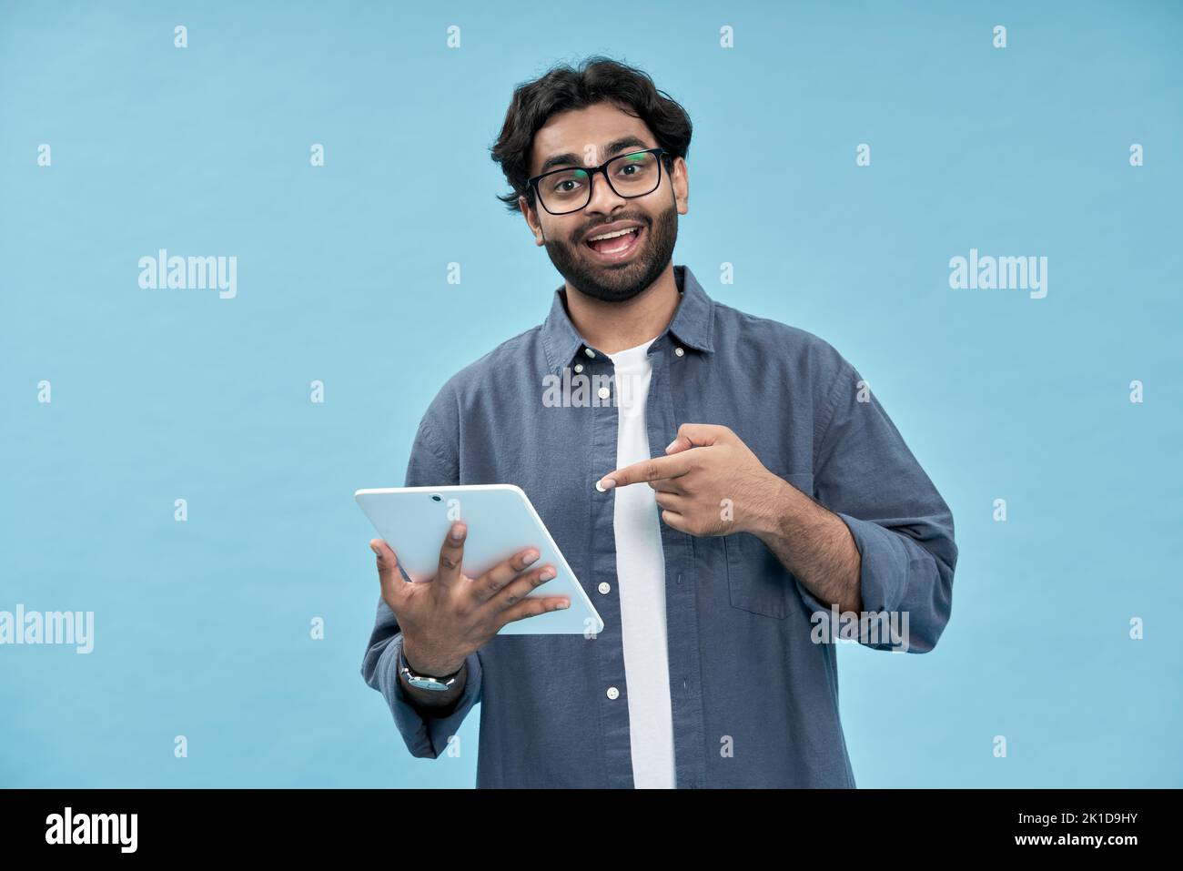 Entusiasmado estudiante árabe que apunta a la tableta digital que presenta el nuevo producto en línea. Foto de stock