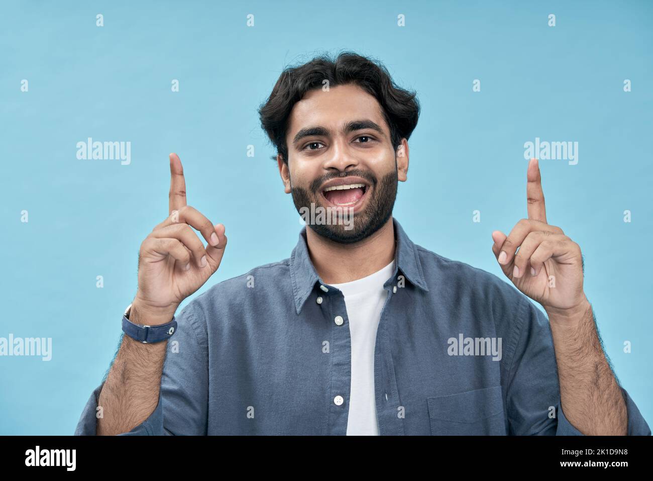 Hombre árabe emocionado señalando encima de la oferta del ecommerce de publicidad aislada en azul. Foto de stock