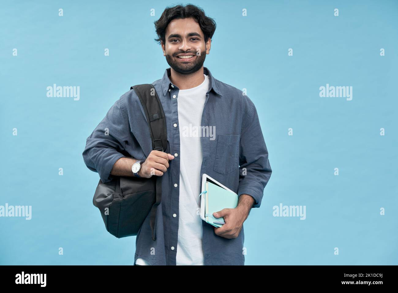 Estudiante joven árabe sonriente de pie aislado sobre fondo azul. Foto de stock