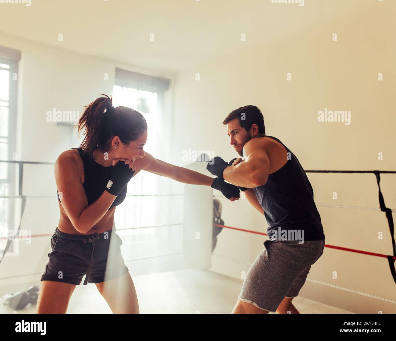 Dos jóvenes atletas se lanzan sin guantes en un ring de boxeo. Dos boxers que tienen una sesión de entrenamiento en un gimnasio de boxeo. Foto de stock