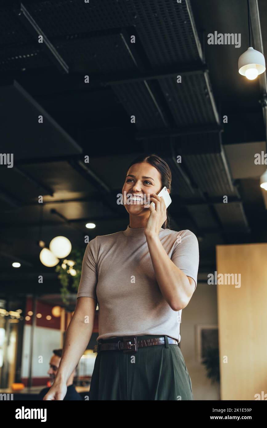Mujer de negocios que recibe una llamada telefónica en un espacio de trabajo conjunto. Feliz joven empresaria sonriendo mientras se comunicaba con sus clientes. Empresaria w Foto de stock