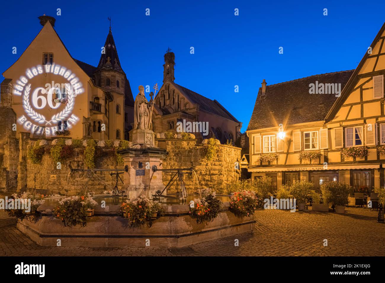 Una noche de verano en la plaza principal (con la fuente de Saint-Léon) en el pueblo de Eguisheim en Alsacia francesa. La edición de 60th del Enólogo Foto de stock
