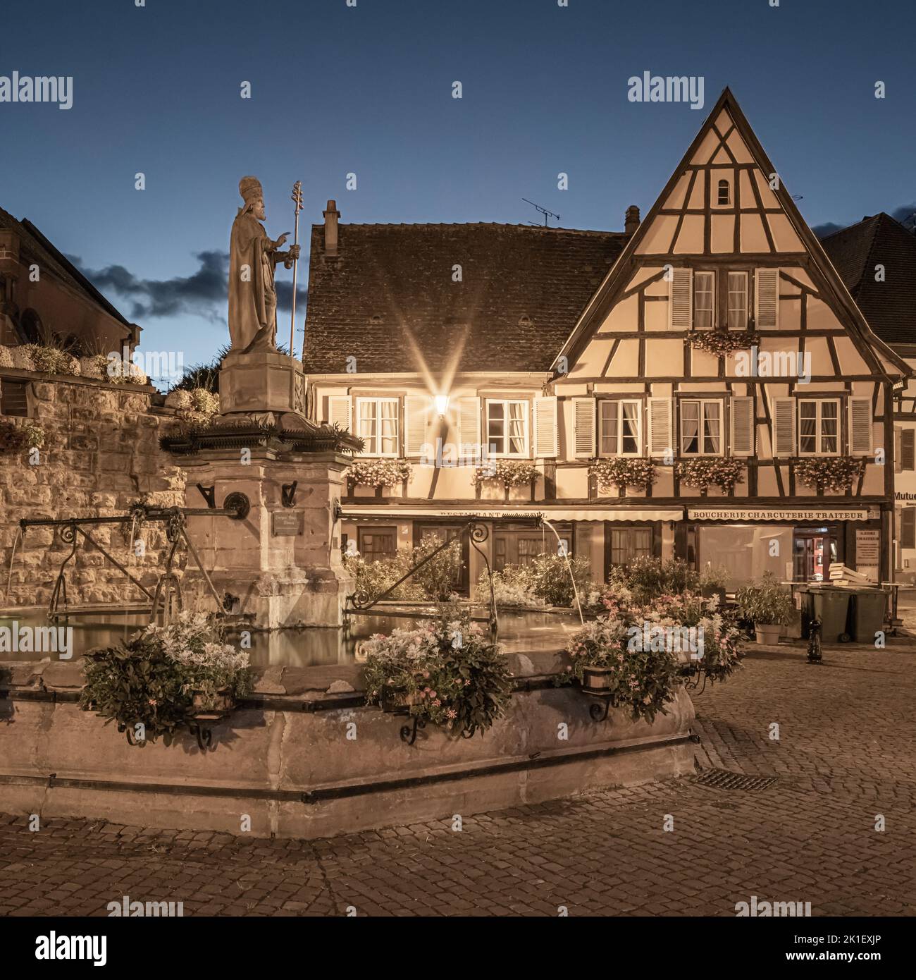 Una tarde de verano después de la puesta del sol en la plaza principal (con la fuente de Saint-Léon) en el pueblo de Eguisheim en la Alsacia, Francia. Foto de stock