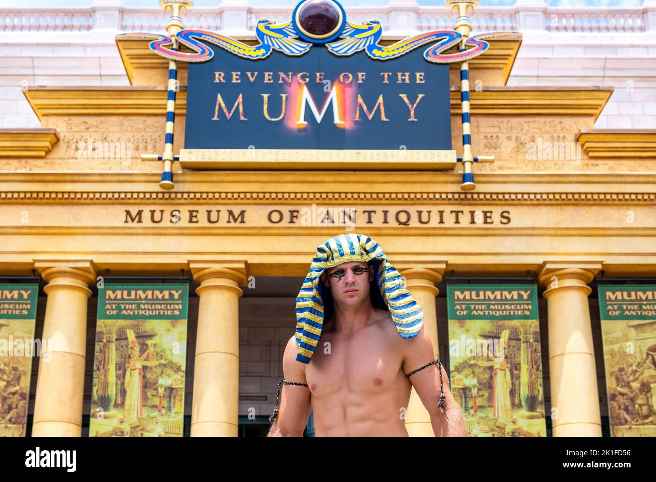 Un animador masculino que actúa frente a la atracción La venganza de la momia. El edificio tiene un cartel que lee el Museo de Antigüedades. Foto de stock