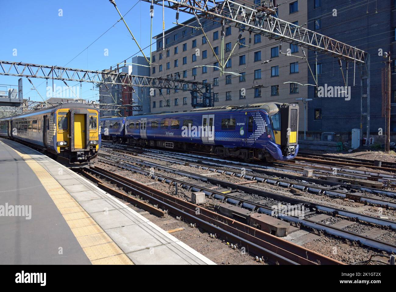 Un tren Siemens Clase 380 Desiro Electric y un tren Clase 156 Super Sprinter Diesel salen de Glasgow Central Station, Escocia, Reino Unido Foto de stock