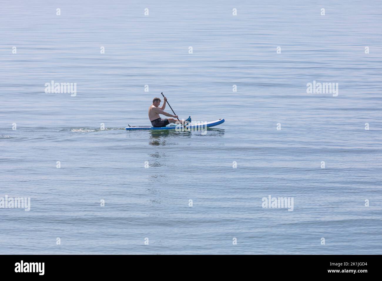 Una frontera solitaria del remo en un mar azul tranquilo Foto de stock