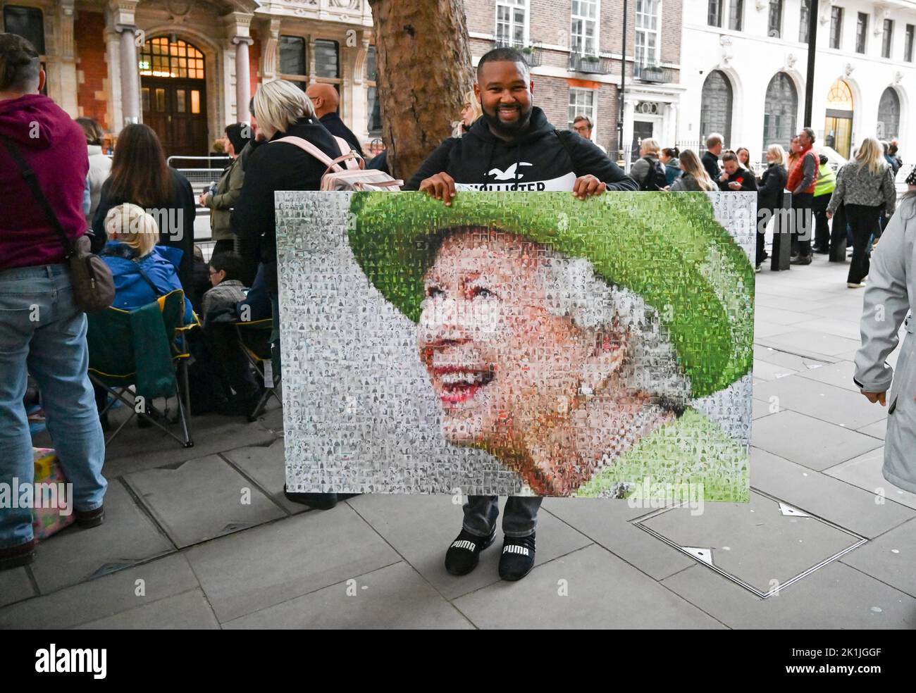 Londres Reino Unido 19th de septiembre de 2022 - Un hombre lleva un retrato grande de la Reina mientras las multitudes se reúnen cerca de Parliament Square en Londres para obtener una vista del funeral de la Reina Isabel II : crédito Simon Dack / Alamy Live News Foto de stock