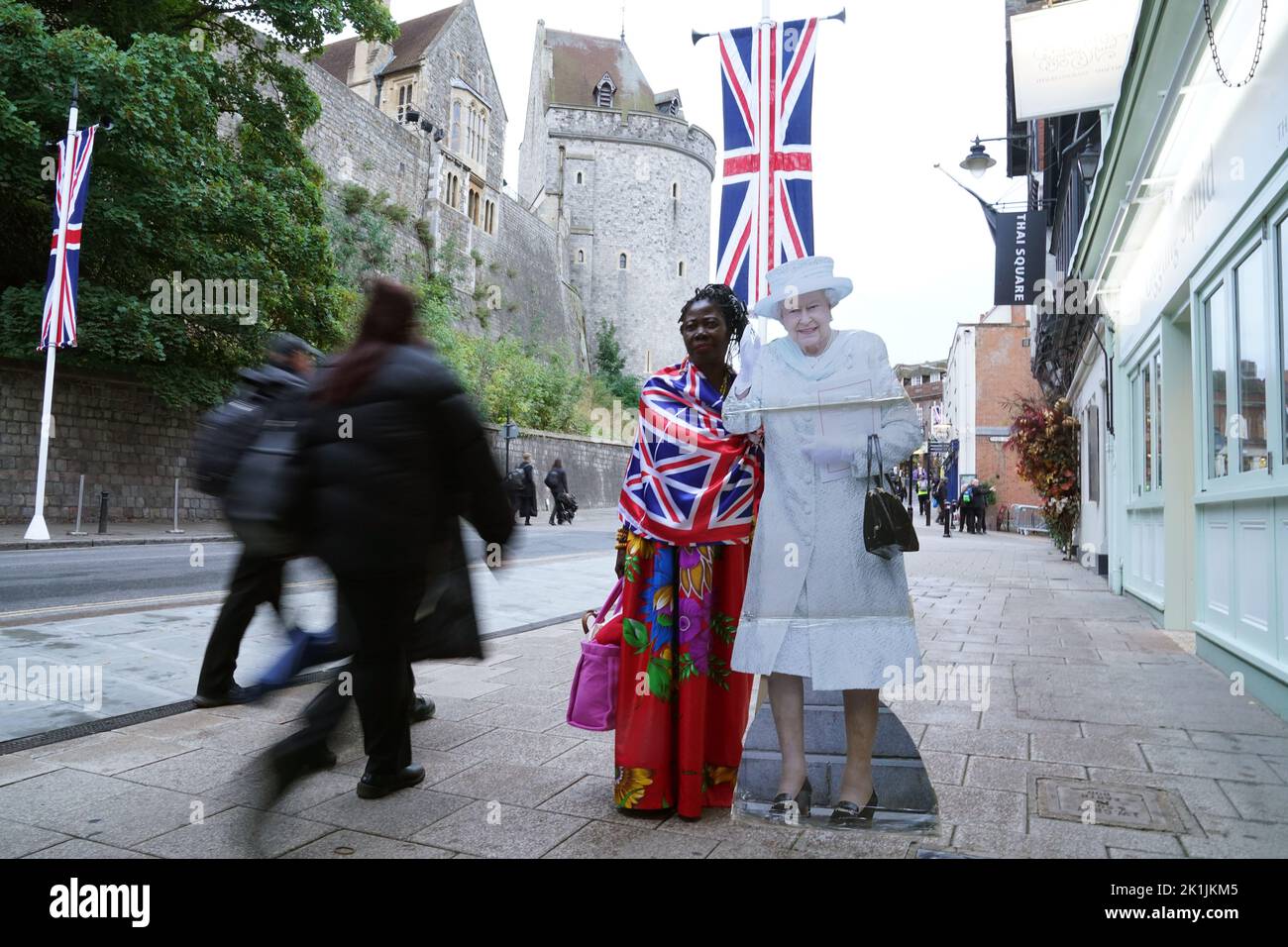 Un miembro del público de pie junto a un corte de cartón de la Reina Isabel II en Windsor, Berkshire, antes del funeral estatal de la Reina Isabel II el lunes. Fecha de la foto: Lunes 19 de septiembre de 2022. Foto de stock