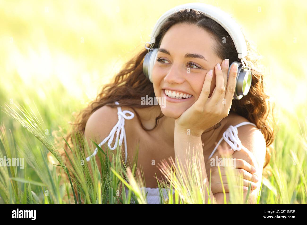 Mujer feliz con auriculares riendo escuchando música en un campo Foto de stock