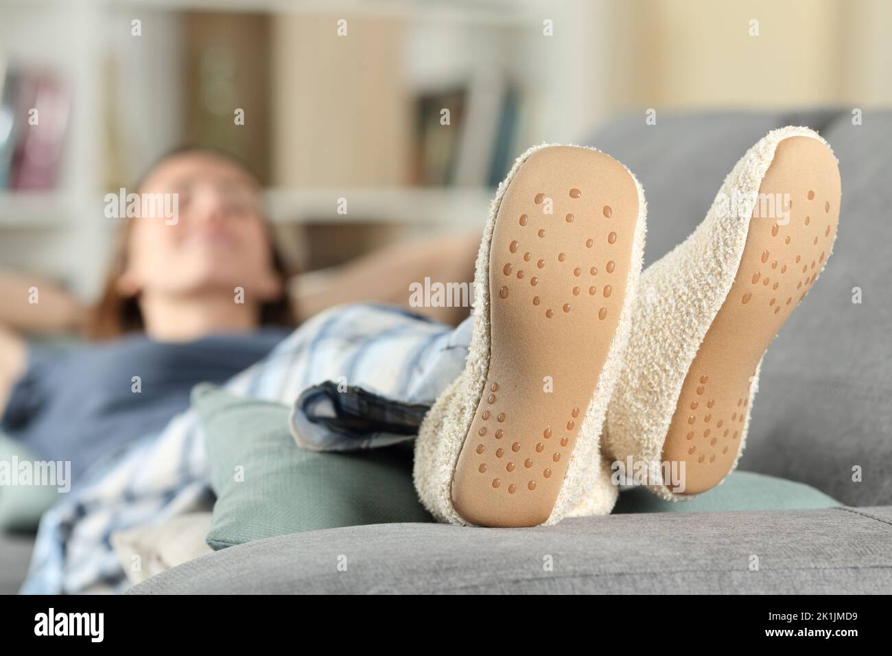 Mujer feliz con zapatillas descansando en un sofá en casa Foto de stock
